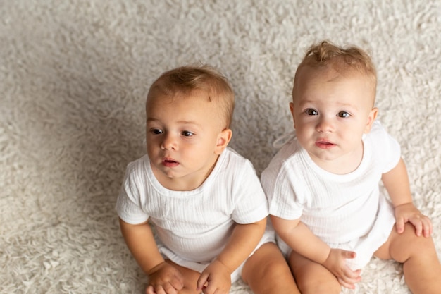 Photo twin boys sitter twin brothers at the age of one year old