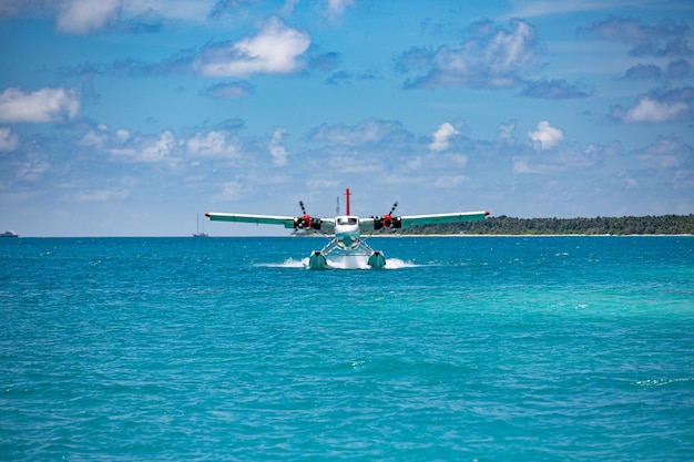 Twin otter red seaplane landing at Maldives. Luxury travel transportation in tropical sea lagoon