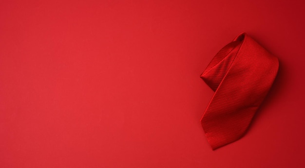 Photo twisted silk red tie on a red background copy space