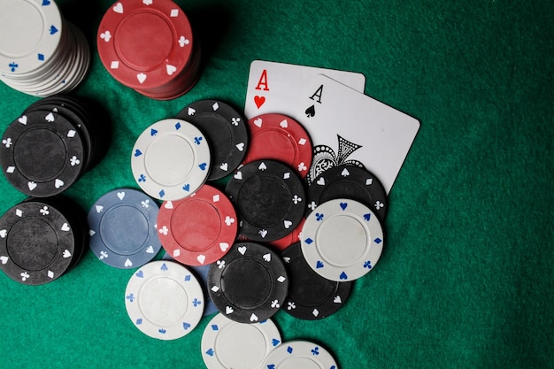 two aces in on the green gaming table. two playing cards and poker chips on a green casino table.