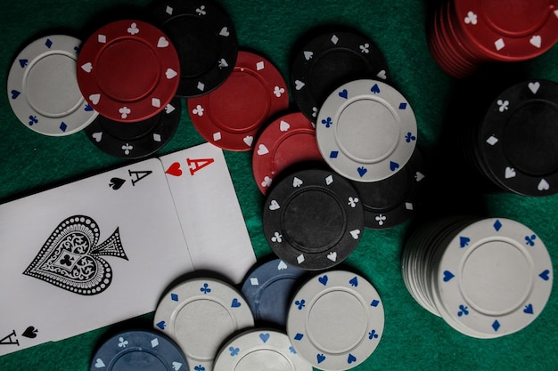 two aces in on the green gaming table. two playing cards and poker chips on a green casino table.