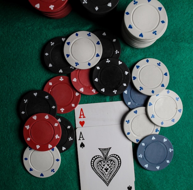 two aces in on the green gaming table. two playing cards and poker chips on a green casino table.