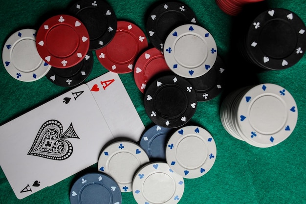 two aces in on the green gaming table. two playing cards and poker chips on a green casino table.