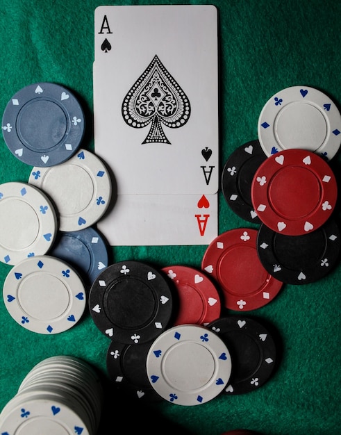 two aces in on the green gaming table. two playing cards and poker chips on a green casino table.