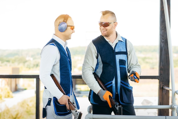 Two adult mans in sunglasses and a rifle vest practicing fire weapon shooting