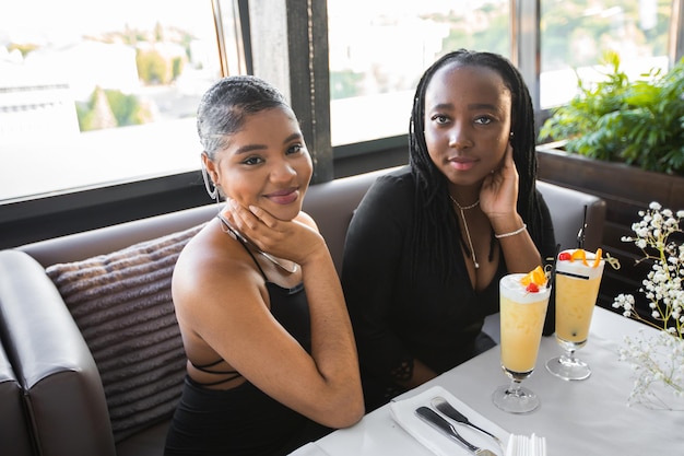 two african girlfriends in a restaurant with drinks at an event