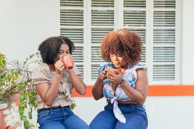 Two Afro women friends enjoying coffee in the cafeteria