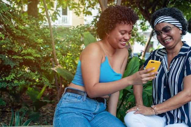 Two Afro women with cell phones in the park