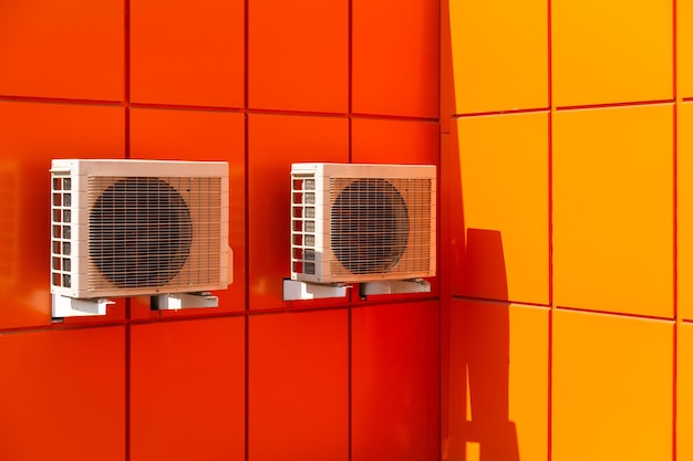 Two air compressors installation on orange wall outside