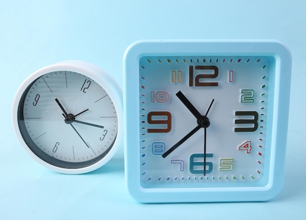 Two alarm clocks on blue background