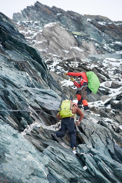 Two alpinists climbing rocky mountain