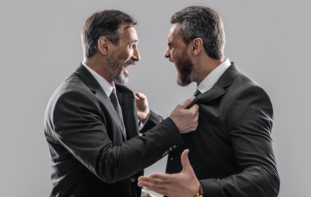 two arguing businessmen shout in conflict isolated on grey background businessmen have conflict in studio conflict of businessmen shouting photo of businessmen conflict with anger