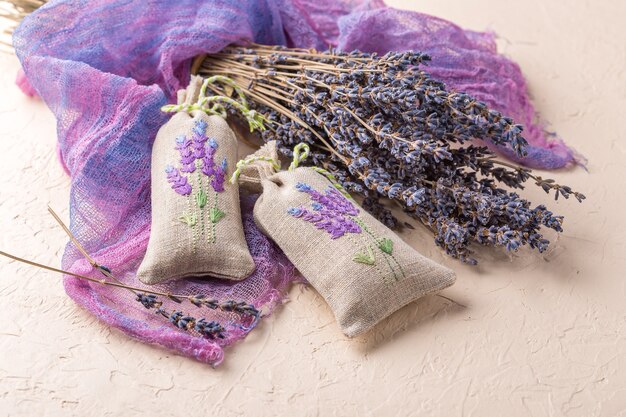 Two aromatic embroidered sachets filled with dried lavender and a bouquet of dry lavender