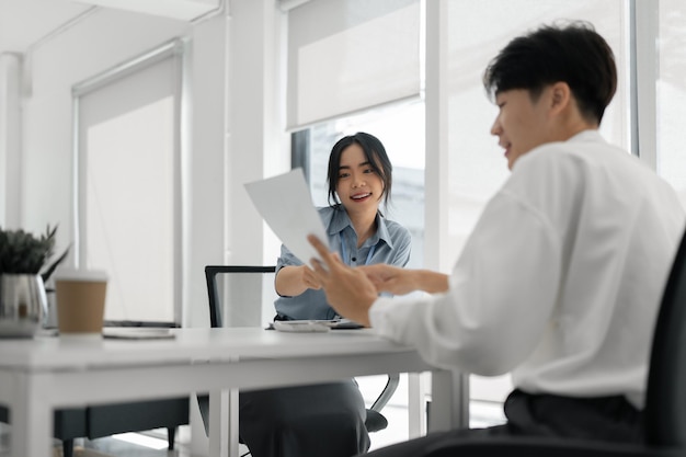 Two Asian colleagues discussing work Businessman holding a tablet in the office