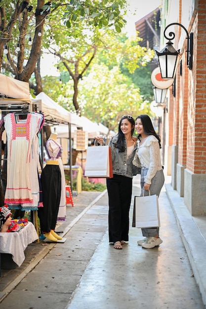 Two Asian female travelers enjoy shopping Northern Thai local products at the city square together