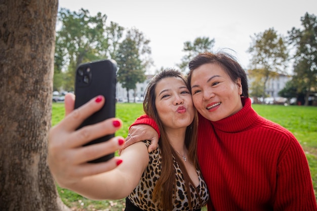 Two Asian friends take a selfie in an openair park happy mature chinese females