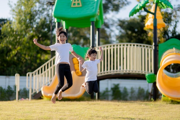 Two Asian little girls having fun on a playground outdoors in summer