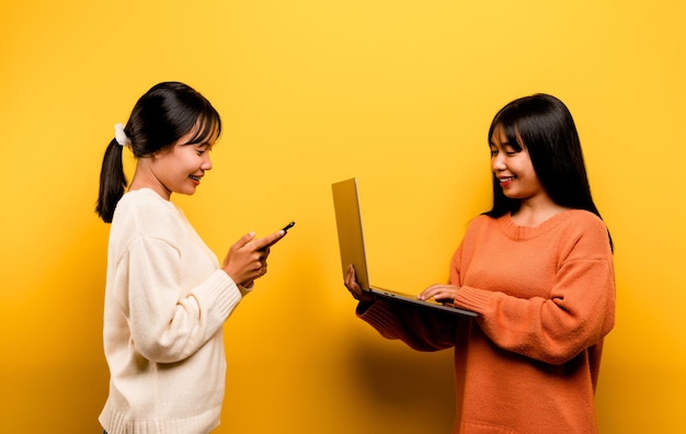 Two Asian women working on laptop and phone at the same time Two of them were communicating online and showing happy smiles