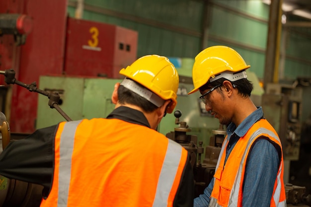 Two Asian worker check status task  in production line.Workplace operation.Two engineer on side maintenance machine.