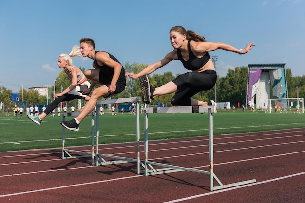 Two athlete woman and man runnner running hurdles at the stadium outdoors