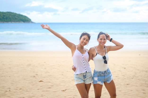 Two attractive women friends enjoying and relaxing on the beach