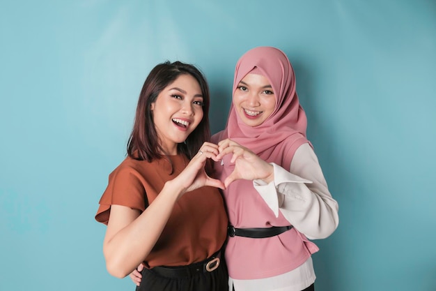 Two attractive young Asian women feels happy and a romantic shapes heart gesture expresses tender feelings and friendship concept