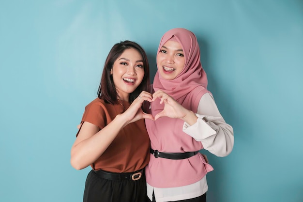 Two attractive young Asian women feels happy and a romantic shapes heart gesture expresses tender feelings and friendship concept