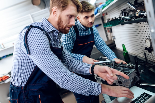 Two Auto Mechanics Work Together In Garage.