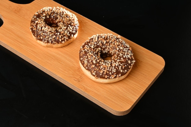 Two bagels on a wooden board with a black background.