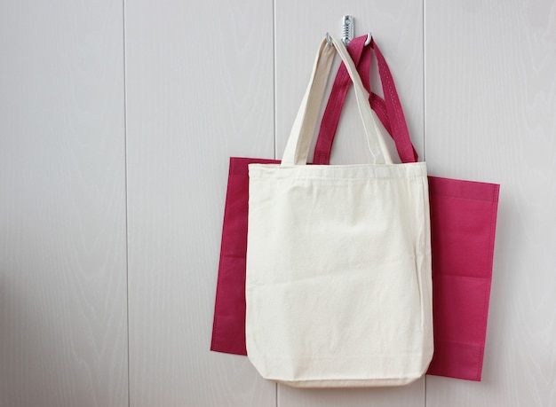 Two bags of fabric hang on a hook on wooden wall