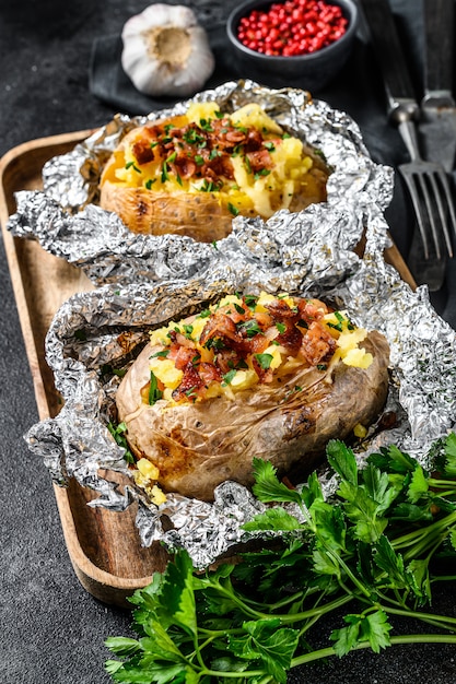 Two baked potatoes with bacon, green onion and cheese.