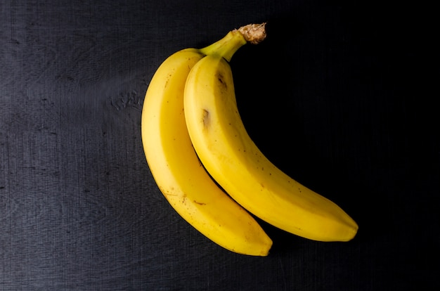 Two bananas on black background.