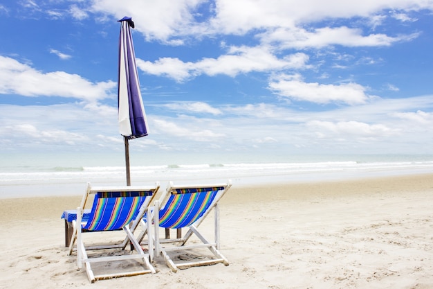 Two beach lounge chairs and tent on beach