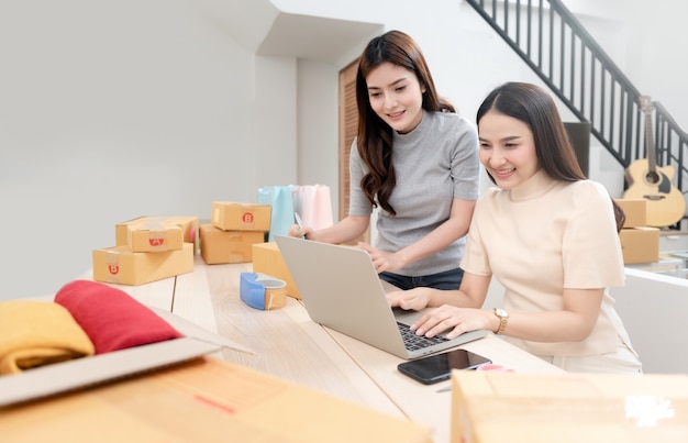 Two beautiful Asian women are checking orders by laptops via the internet.