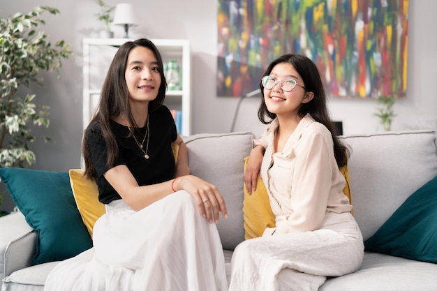 Two beautiful attractive best friends spend time together on the sofa in the living room