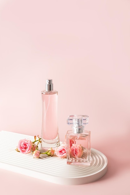 Two beautiful bottles of women's perfume or eau de parfum on a white podium with small pink roses Front vertical view A copy space