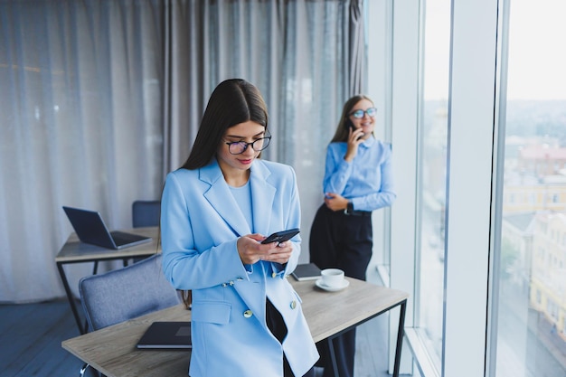 Two beautiful business women in the office and doing business Business woman in office with glasses and phone Woman manager in glasses and white shirt in the office Head of working day