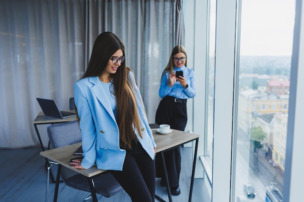 Two beautiful business women in the office and doing business Business woman in office with glasses and phone Woman manager in glasses and white shirt in the office Head of working day