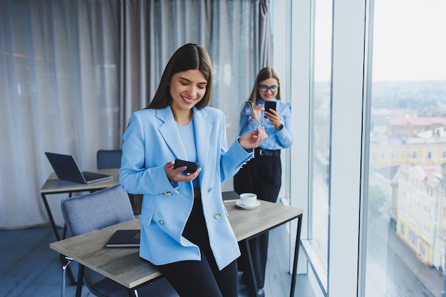 Two beautiful business women in the office and doing business Business woman in office with glasses and phone Woman manager in glasses and white shirt in the office Head of working day