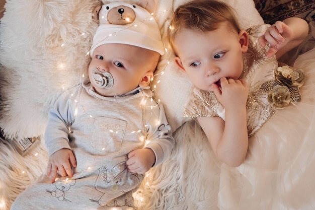 Two Beautiful caucasian children rests with a lot of lights around them in christmas night together