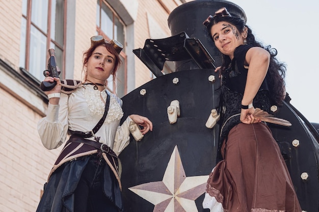 Two beautiful girl in steampunk clothes on the background of the train