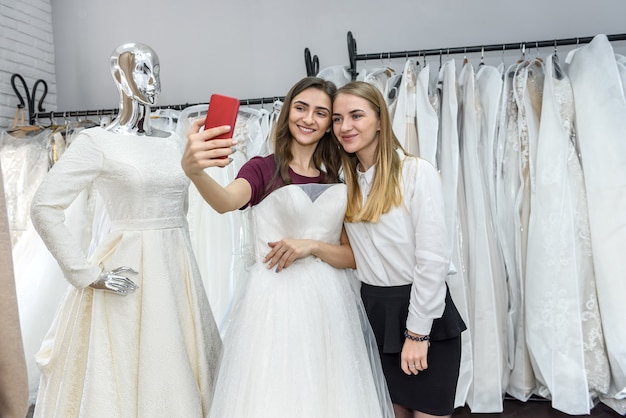 Photo two beautiful girls making selfie in wedding salon