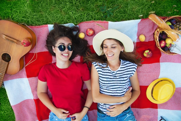 Two beautiful girls in sunglasses having fun on a picnic in the forest Top view