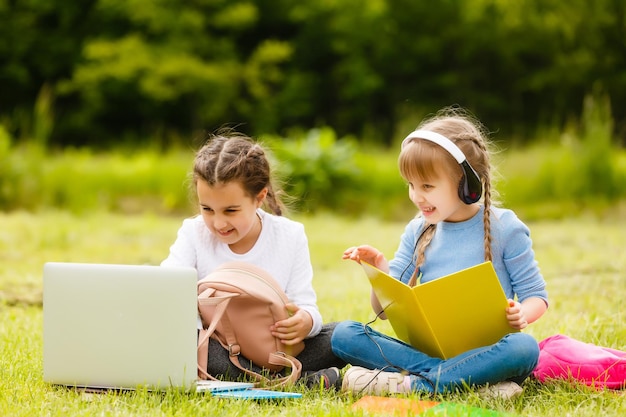 Two beautiful sisters do their homework during quarantine. Children use gadgets for learning. Education, distance learning, home schooling during quarantine