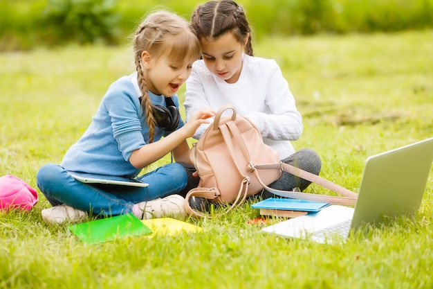 Two beautiful sisters do their homework during quarantine. Children use gadgets for learning. Education, distance learning, home schooling during quarantine