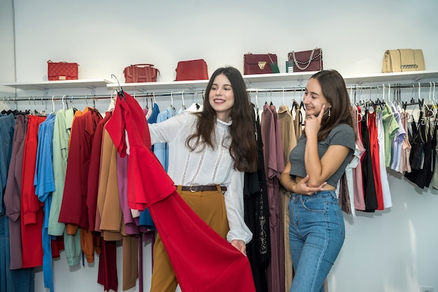 Two beautiful smile friends choosing and shopping at clothing retail store. Black friday