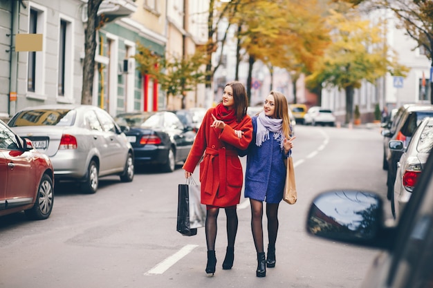 two beautiful and stylish girlfriends walking around the city with packages and shopping