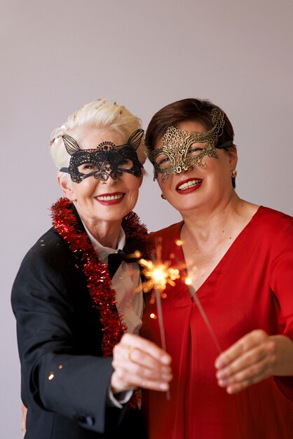 Two beautiful stylish mature senior women in carnival masks with sparkles celebrating new year