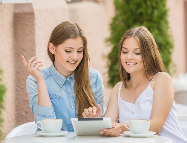 Two beautiful young women sitting at summer cafe.