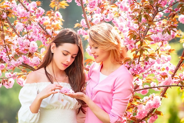 Two beauty spring girls with blooming sakura cherry flover